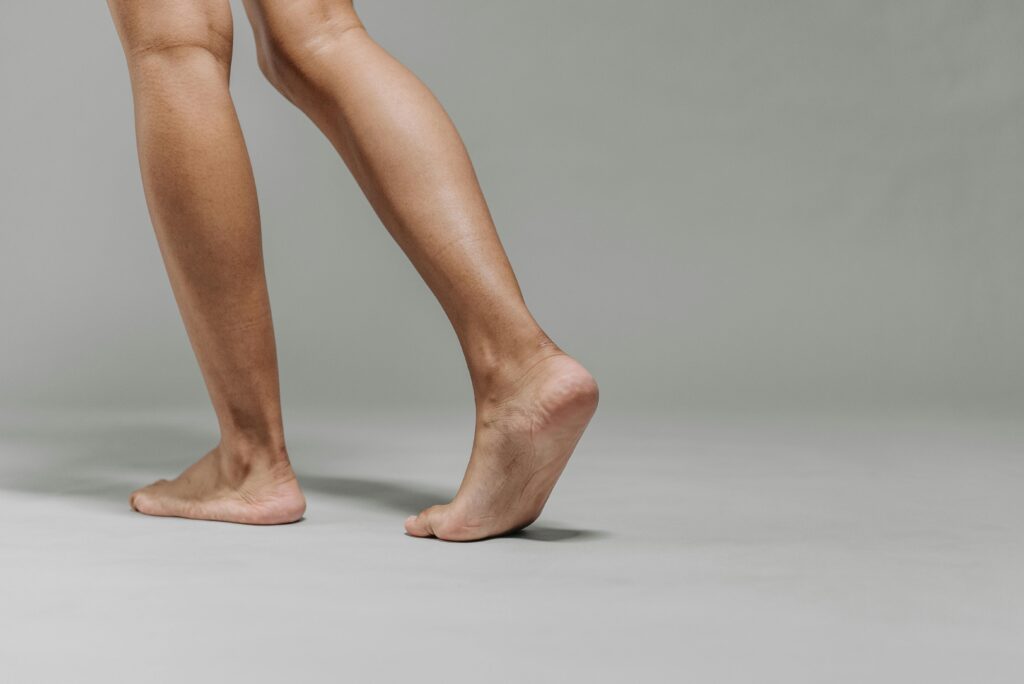Close-up of adult bare feet on a neutral grey background, focused on walking.